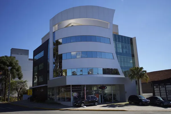Prédio comercial moderno com painéis de revestimento em ACM cinza escuro, esquadria de alumínio e vidros espelhados refletivos.