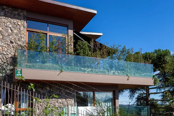 Visão detalhada de guarda-corpo residencial composto por painéis de vidro temperado e fixadores metálicos de alta resistência.